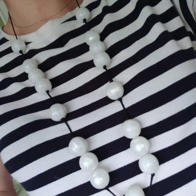 A beautiful white simmering beaded necklace from teething jewellery brand Gumigem. Round pearl beads are strung into a silky black cord with a safety breakaway fastening.  The necklace is approximately 80cm in length but can be cut shorter to size if required. The beads are made from the highest quality non-toxic, BPA, PVC, lead, latex and phthalate free silicone, and can be washed (even in the dishwasher) and sterilised, if required.