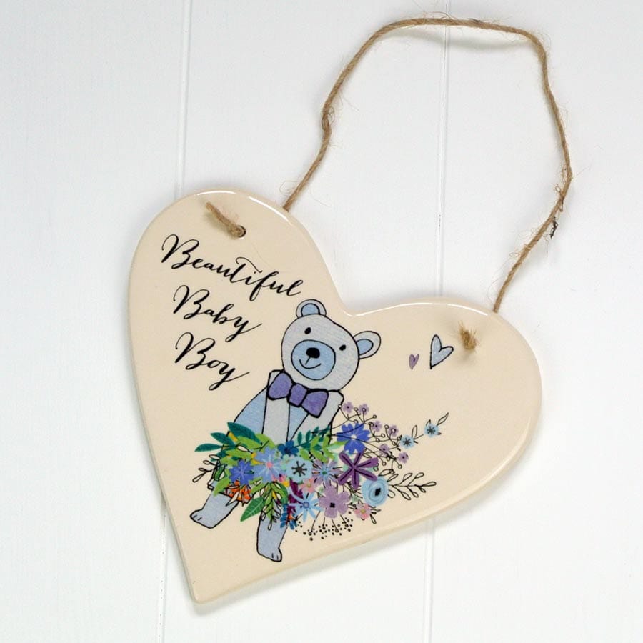 A contemporary ceramic hanging heart perfect for any newborn boys bedroom.  Made by British brand Peel and Sardine, this decoration features a really cute little bear holding a bunch of blue flowers.